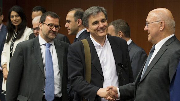 French Finance Minister Michel Sapin (right) shakes hands with his Greek counterpart Euclid Tsakalotos at a Eurogroup meeting in Brussels on Monday.