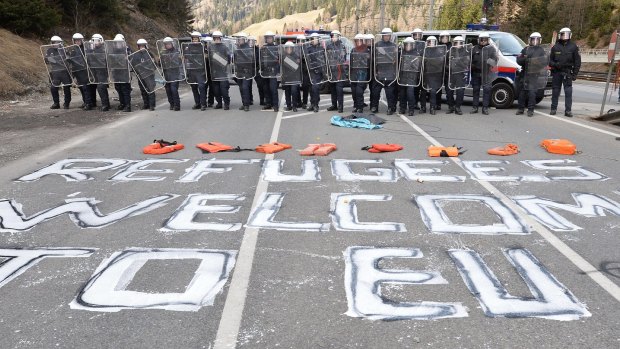 "Refugees welcome to EU" is painted on a street in front of Austrian police officers in the village of Brenner on the Italian-Austrian border earlier this month. 