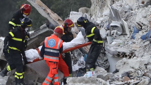 Rescuers recover a lifeless body from a collapsed house