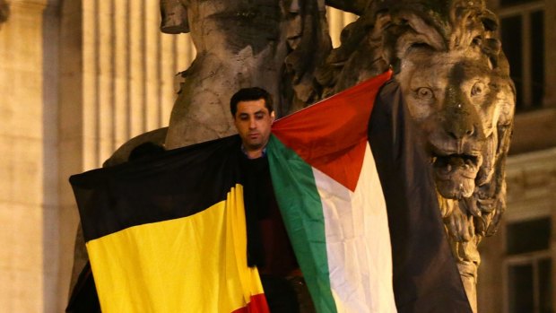 A man waves a Belgian and Palestinian flag as a mark of solidarity at the Place de la Bourse in Brussels on Tuesday. 
