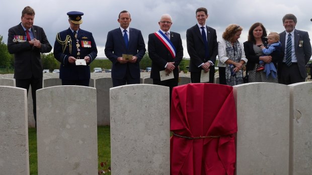 Tony Abbott and the official party, including members of the Kirkland family, before the new headstone of Corporal Athol Kirkland.