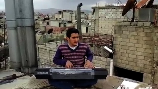 Ayham al-Ahmad rehearses a song on a rooftop in Yarmouk refugee camp.