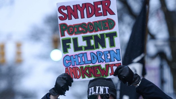 Mike Ahrens of Muskegon poses for photo with his sign about Flint's water crisis in Ann Arbor, Michigan. 