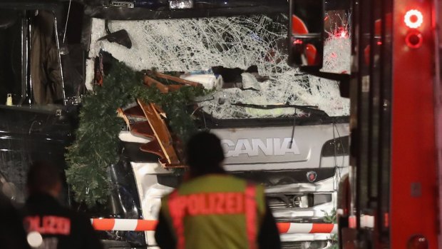 Police stand in front of a black lorry that ploughed through a Christmas market in Berlin.