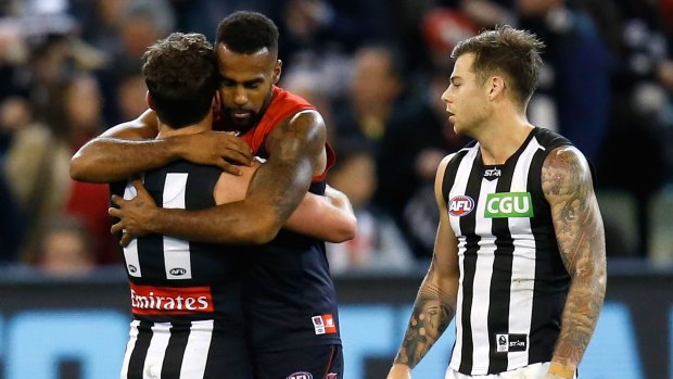 Jarryd Blair of the Magpies (left) and Heritier Lumumba of the Demons embrace as Jamie Elliott of the Magpies looks on.