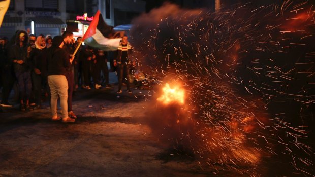 Palestinian protesters burn tires as they wave their national flags during a protest at the main square in Gaza City.