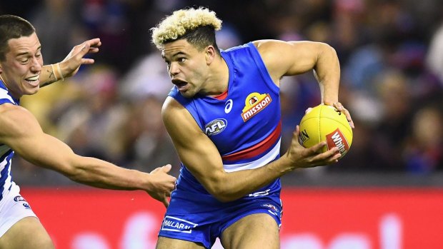 Jason Johannisen of the Bulldogs is chased by Nathan Hrovat of the Kangaroos during the round 14 AFL match between the Western Bulldogs and the North Melbourne. 