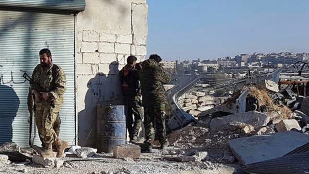 Kurdish fighters watch people flee from rebel-held eastern neighbourhoods of Aleppo.