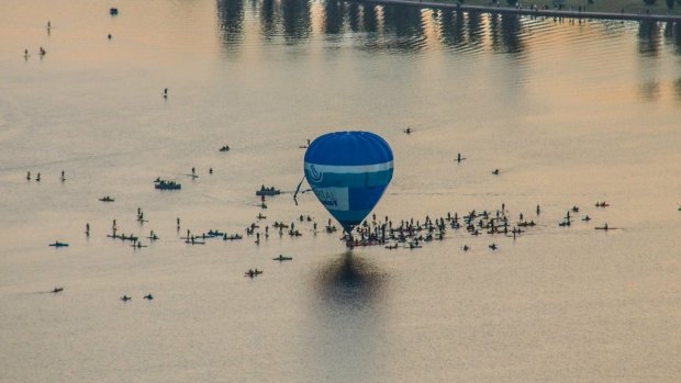 A beautiful shot by Paul Jurak of the Capital Chemist balloon skimming the lake, surrounded by kayaks and stand-up boarders.