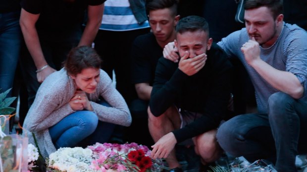 People mourn near the crime scene at OEZ shopping centre the day after a shooting spree left nine victims dead.