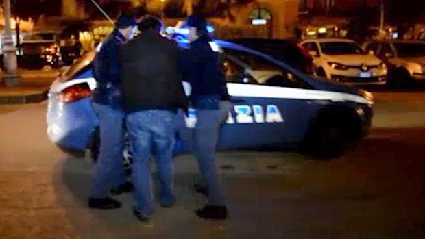 Italian police escort a man into a police car in the southern city of Salerno on Sunday. Police identified the man as an Algerian wanted in connection with the recent terror attacks.