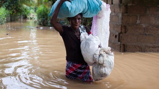 Assilia Joseph carries her belongings through flood waters in Haiti.