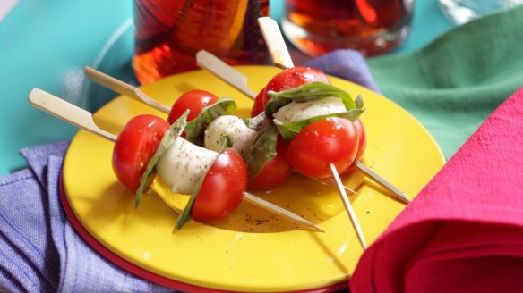 Caprese skewers with cherry tomatoes served with festive plates and napkins from Market Import.