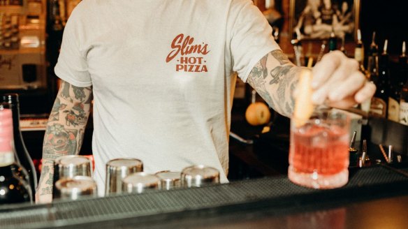 An orange garnish is traditional, as seen at Slim's, but Stanley Tucci's addition of orange juice was not welcomed by bartenders.
