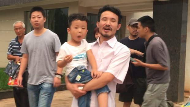 Chinese labour activists Li Zhao and Hua Haifeng (with his son) leave a police station after being released in Ganzhou following their arrest in relation to their investigations into factories used by Ivanka Trump's brand.