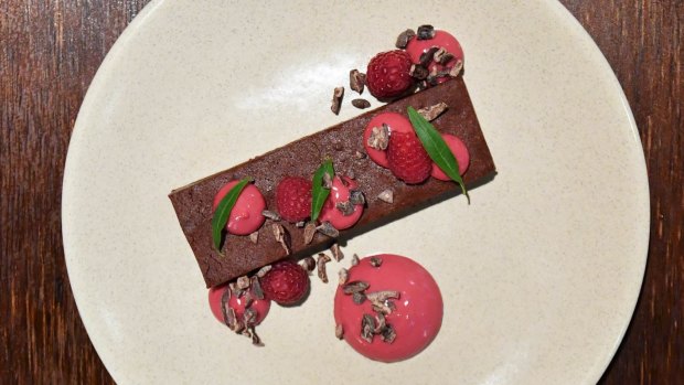 Chocolate torte with raspberry coulis and cocoa nibs.