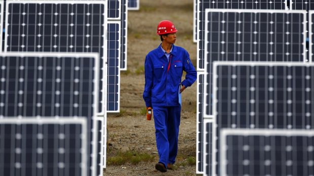 A worker inspects solar panels at a solar farm in Dunhuang, China.