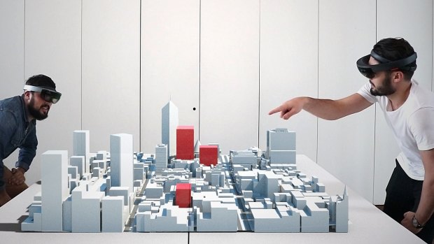 Research assistants look at a shared model, with shadows produced by existing and proposed (in red) building envelopes visualised using a live holographic simulation.
