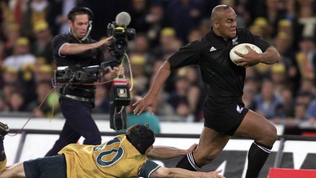 Sheer power: Jonah Lomu beats the tackle of Stephen Larkham in the 39-34 game won by the All Blacks at Stadium Australia.