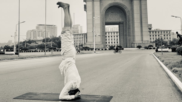 Joachim Bergstrom does a handstand in front of a North Korean landmark.