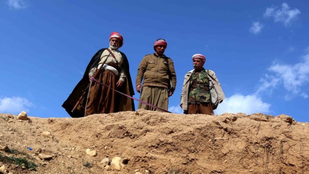 Yazidis look down on a mass grave. 