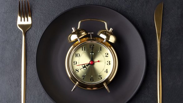 Interval fasting concept with a golden alarm clock on a black plate. Flat lay with copy space. IntermittentÃÂÃÂ fasting generic. skipping breakfast. fasting diet. Downloaded from iStock under the Good Food account.