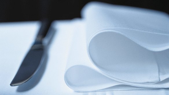 Fork, knife and napkin of a restaurant table setting.