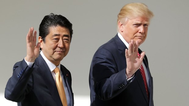 Donald Trump and Shinzo Abe wave while walking to a joint news conference.