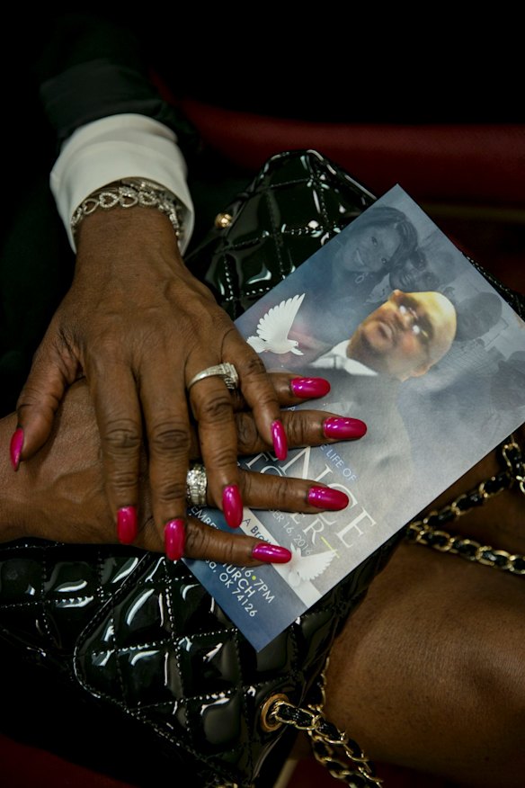 September 2016: A program produced in memory of Terence Crutcher, the 40-year-old unarmed man   shot and killed by police officer Betty Jo Shelby, in the lap of a woman during his funeral in Tulsa, Oklahoma. 