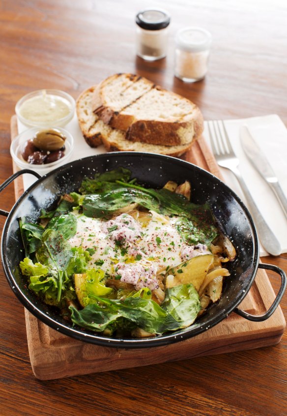 Green Shakshuka on a wooden board with olives and grilled sourdough at Shuk Cafe.