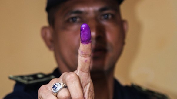 A National Police officer shows his finger after voting in Farol, Dili, on Monday.