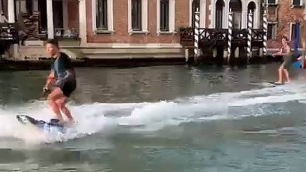  Two foreign tourists speed down Venice's Grand Canal on motorised surfboards.