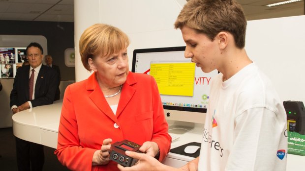 Michael Schultz shows his tricoder to German Chancellor Angela Merkel.