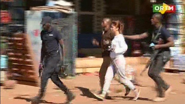 A woman is led away by security from the Radisson Blu Hotel in Mali during the attack.