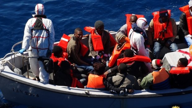 Rescued migrants wear life-jackets as they sit in an Italian navy's boat in the Sicilian Channel, Mediterranean Sea, on Friday.