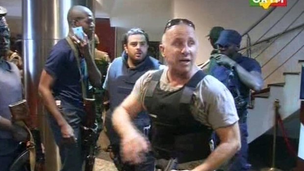 In this TV image taken from Mali TV ORTM, a security officer gives instructions to other security forces before moving against Islamist gunmen inside the Radisson Blu Hotel in Bamako, Mali.