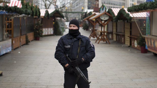 An armed police officer stands guard as the festive stalls remain closed at Berlin Christmas market in Berlin, Germany after a terror attack. 
