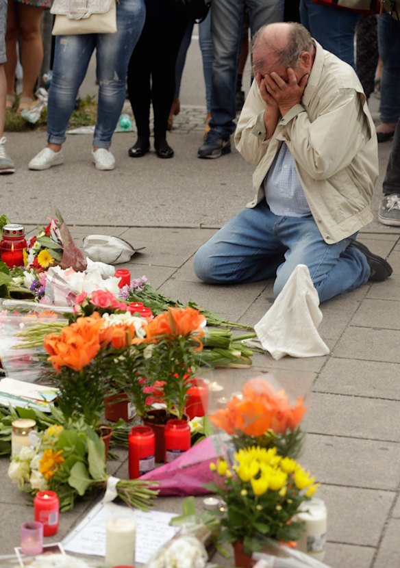 People mourn near the crime scene at OEZ shopping centre the day after the shooting spree.