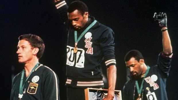 Tommie Smith (centre), and John Carlos (right) salute after winning gold and bronze at the 1968 Olympics.