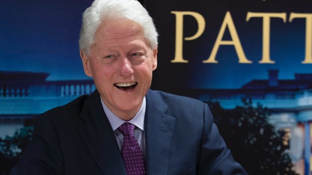 Former President Bill Clinton, left, smiles as he signs autographs during an event to promote his new novel with author James Patterson.