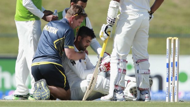 Down, but not out: Ahmed Shehzad is treated after being struck in the head by a bouncer.