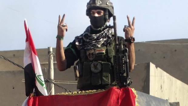 An Iraqi soldier flashes the victory sign after entering the government complex in central Ramadi.