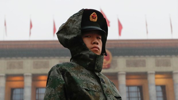 A solder in a raincoat stands watch outside the Great Hall of the People during the opening ceremony of the 19th Party Congress in Beijing.
