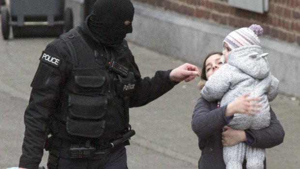 Police evacuate a woman and a small child during a police raid targeting Paris attacks suspect Salah Abdeslam.