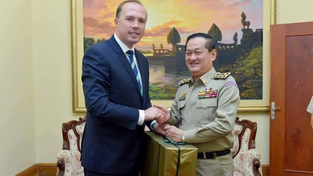 Australian Immigration Minister Peter Dutton presents an Akubra hat to Cambodia's Department of Immigration director-general, Sok Phal.