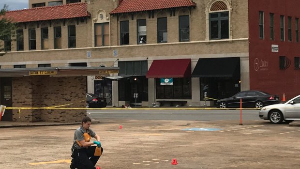 An investigator collects evidence near an Arkansas nightclub where 25 people were shot.