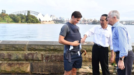 President Joko Widodo and Prime Minister Malcolm Turnbull talk to a father carrying his eight-week-old baby.