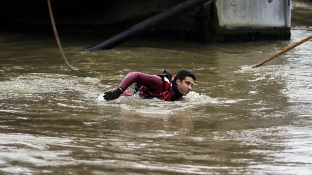 A firefighter swims through the river Seine to help secure boats fixed at the overflowing banks.