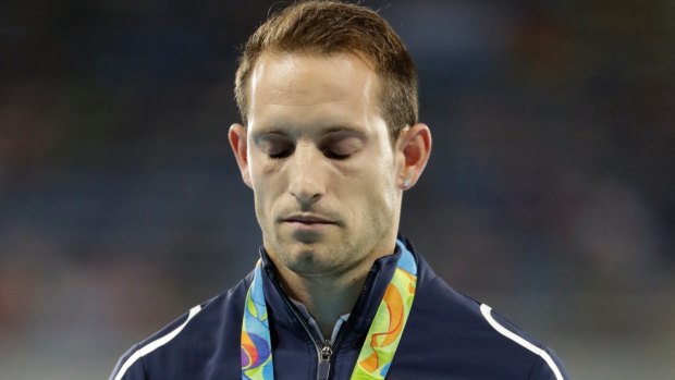France's Renaud Lavillenie stands on the podium with his silver medal during the medals ceremony for the men's pole vault in Rio, while the crowd boos.