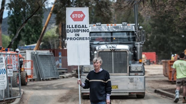Protest organiser John Connelly stops a moving truck outside the ANU construction site.